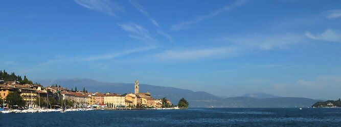 Action beliebte Urlaubsziele am Gardasee -  Mit einer Fläche von 370 km² ist der Gardasee der größte See Italiens. Es liegt am Fuße der Alpen und erstreckt sich über drei Staaten: Lombardei, Venetien und Trentino. Die maximale Tiefe des Sees beträgt 346 m, er hat eine längliche Form und sein nördliches Ende ist sehr schmal. Dort ist der See von den Bergen der Gruppo di Baldo umgeben. Du trittst aus deinem gemütlichen Hotelzimmer und es begrüßt dich die warme italienische Sonne. Du blickst auf den atemberaubenden Gardasee, der in zahlreichen Blautönen schimmert - von tiefem Dunkelblau bis zu funkelndem Türkis. Majestätische Berge umgeben dich, während die Brise sanft deine Haut streichelt und der Duft von blühenden Zitronenbäumen deine Nase kitzelt. Du schlenderst die malerischen, engen Gassen entlang, vorbei an farbenfrohen, blumengeschmückten Häusern. Vereinzelt unterbricht das fröhliche Lachen der Einheimischen die friedvolle Stille. Du fühlst dich wie in einem Traum, der nicht enden will. Jeder Schritt führt dich zu neuen Entdeckungen und Abenteuern. Du probierst die köstliche italienische Küche mit ihren frischen Zutaten und verführerischen Aromen. Die Sonne geht langsam unter und taucht den Himmel in ein leuchtendes Orange-rot - ein spektakulärer Anblick.